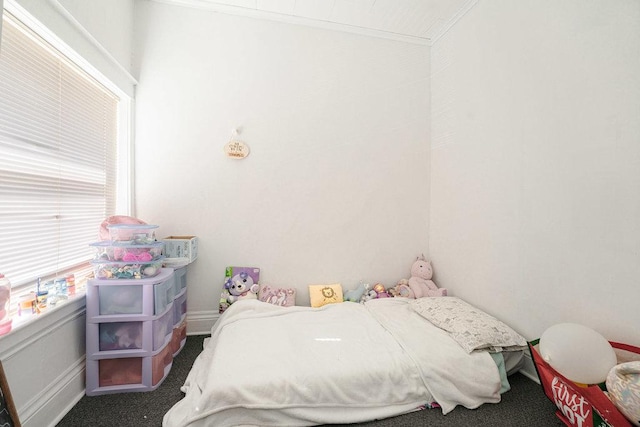 bedroom with crown molding and dark carpet