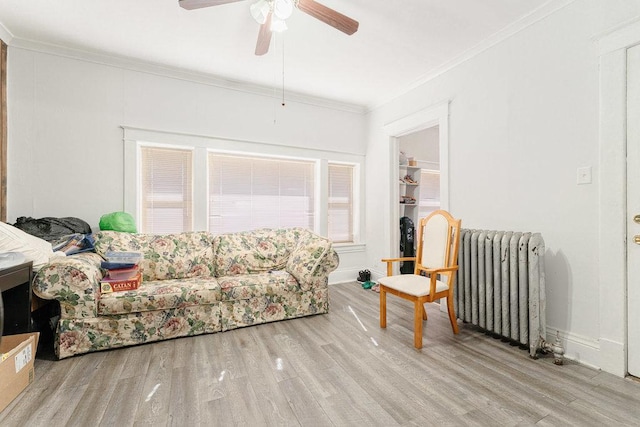 living room with radiator heating unit, light wood-type flooring, and ornamental molding