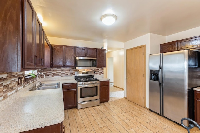 kitchen with dark brown cabinetry, sink, tasteful backsplash, light hardwood / wood-style floors, and appliances with stainless steel finishes