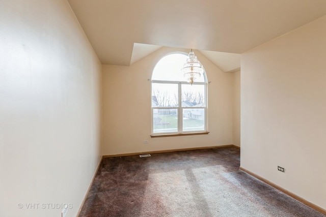 empty room with dark carpet, lofted ceiling, and a chandelier