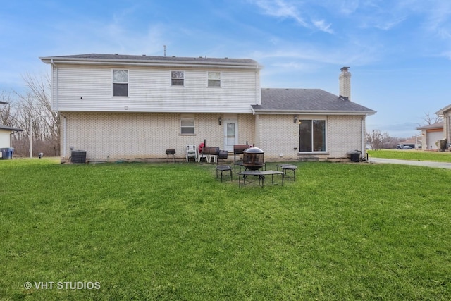 back of house featuring central air condition unit, a lawn, and a fire pit