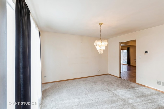 spare room with carpet floors and a notable chandelier