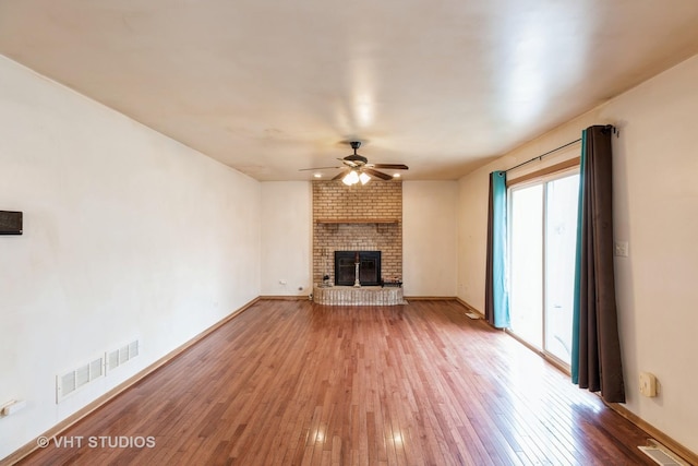 unfurnished living room with ceiling fan, a fireplace, and wood-type flooring