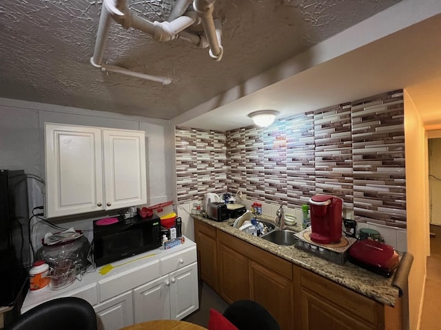 kitchen with white cabinets, a textured ceiling, backsplash, and sink