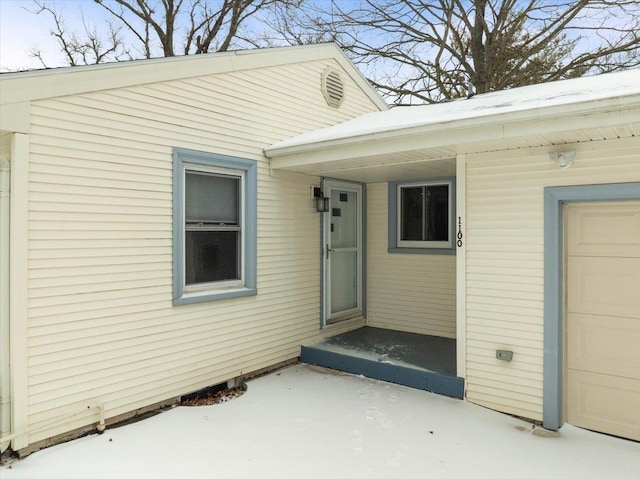 snow covered property entrance featuring a garage