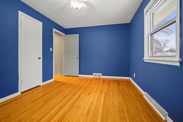 unfurnished bedroom with ceiling fan, light hardwood / wood-style floors, and a baseboard radiator