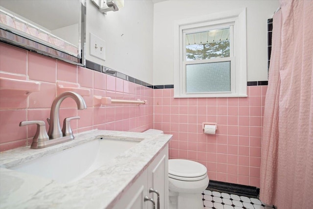 bathroom with vanity, toilet, and tile walls