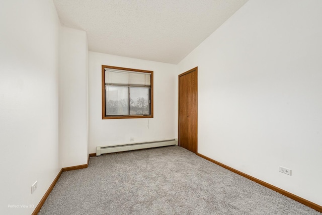 carpeted spare room featuring a textured ceiling, vaulted ceiling, and baseboard heating