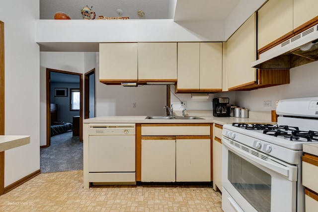 kitchen featuring a textured ceiling, cream cabinets, white appliances, and sink