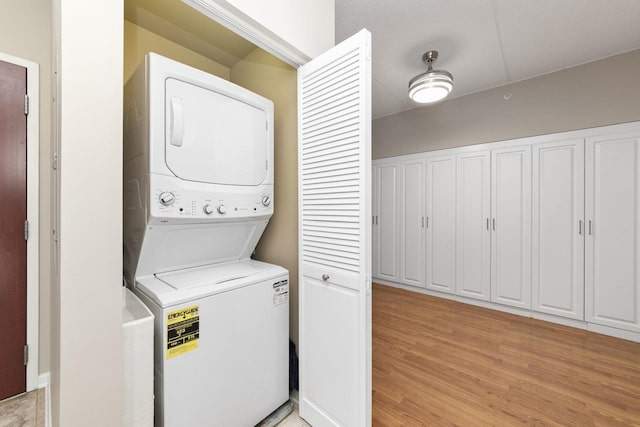 laundry room featuring light hardwood / wood-style floors and stacked washer and clothes dryer