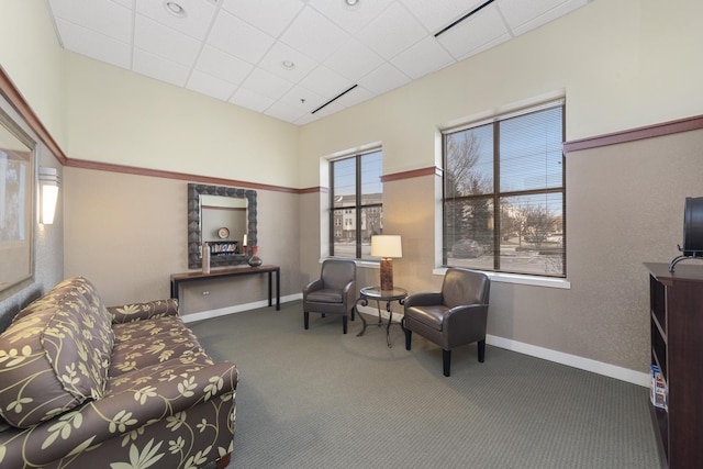 sitting room featuring a drop ceiling and dark carpet