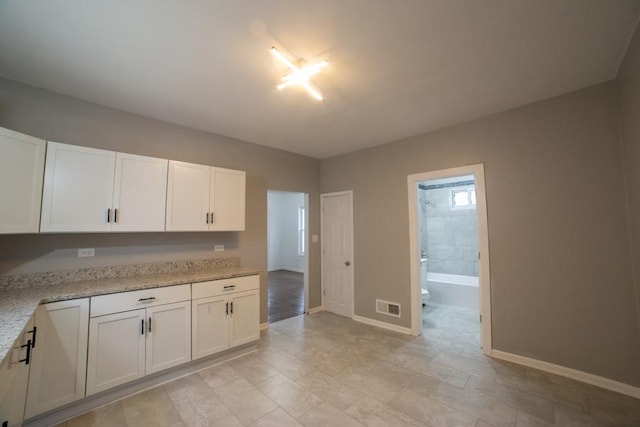 kitchen featuring white cabinets and light stone countertops