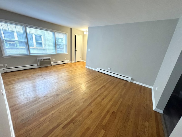 empty room with a wall mounted air conditioner, wood-type flooring, and a baseboard heating unit