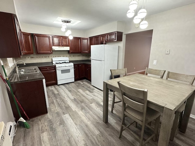 kitchen with pendant lighting, white appliances, a baseboard heating unit, sink, and light wood-type flooring