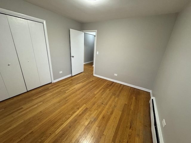 unfurnished bedroom featuring light hardwood / wood-style floors, a closet, and a baseboard radiator