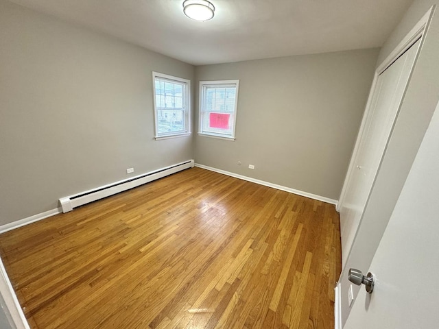 unfurnished bedroom with a baseboard radiator, light hardwood / wood-style flooring, and a closet