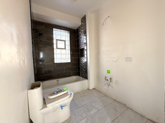 bathroom featuring tiled shower / bath combo and toilet