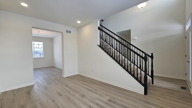 stairs featuring hardwood / wood-style floors and a notable chandelier