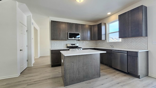 kitchen with a center island, backsplash, light wood-type flooring, appliances with stainless steel finishes, and dark brown cabinets