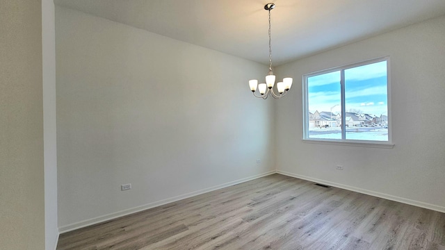 unfurnished room with light hardwood / wood-style floors and an inviting chandelier