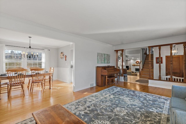 living room featuring crown molding, wood-type flooring, and an inviting chandelier