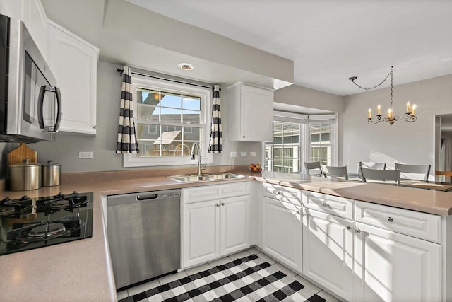 kitchen featuring white cabinets, sink, appliances with stainless steel finishes, and a chandelier