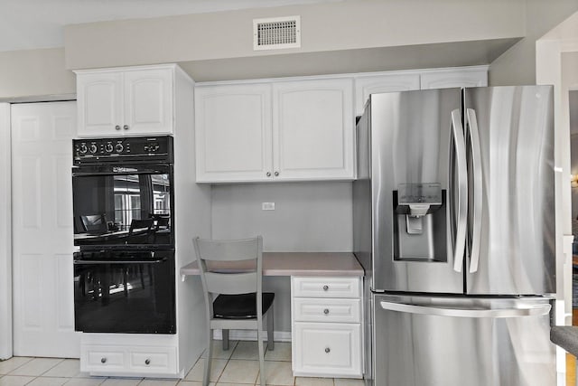 kitchen featuring stainless steel fridge with ice dispenser, black double oven, white cabinets, and light tile patterned floors