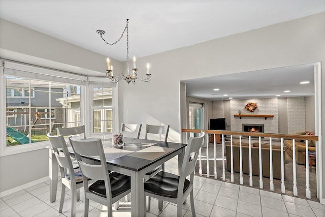 tiled dining area featuring a fireplace, a chandelier, and brick wall