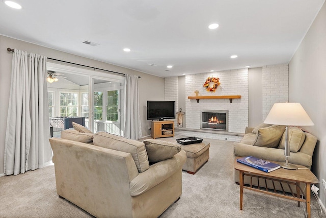 living room with ceiling fan, light colored carpet, and a brick fireplace