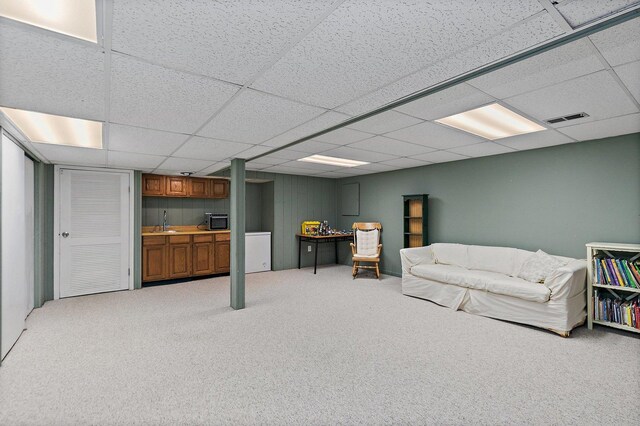 living room with a paneled ceiling, sink, and carpet floors