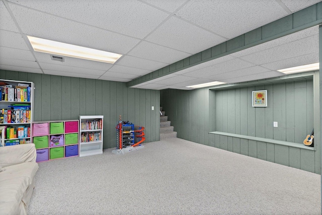 playroom featuring a paneled ceiling, wooden walls, and carpet floors