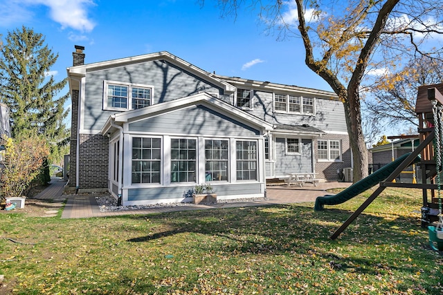 rear view of property featuring a playground, a patio area, and a lawn