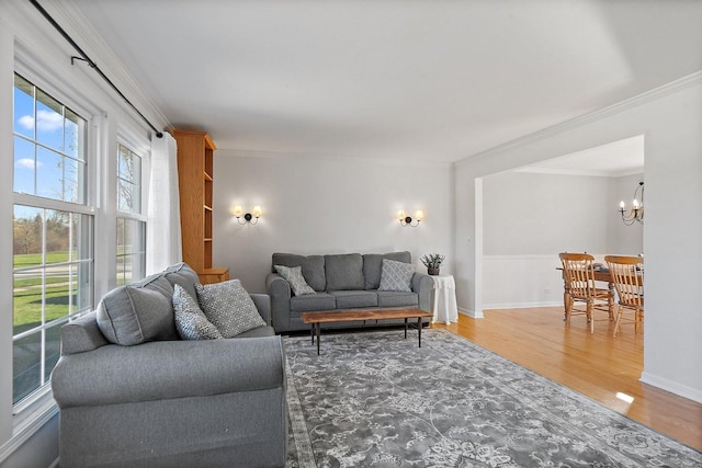 living room with hardwood / wood-style floors, ornamental molding, and a notable chandelier