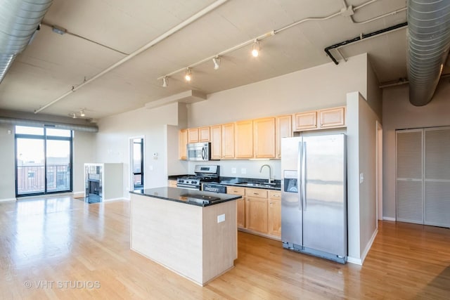 kitchen featuring light hardwood / wood-style flooring, light brown cabinetry, a towering ceiling, appliances with stainless steel finishes, and sink