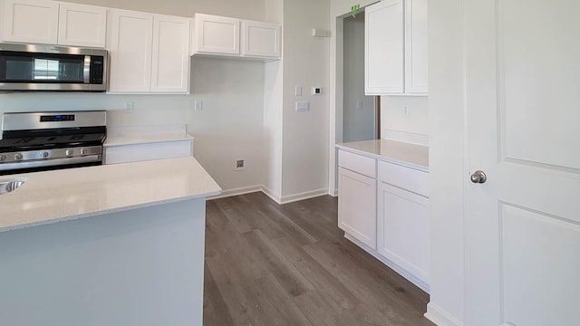 kitchen featuring white cabinets, dark hardwood / wood-style floors, light stone countertops, and stainless steel appliances