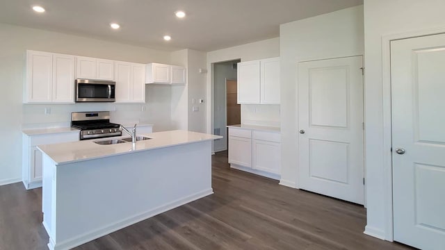 kitchen with stainless steel appliances, a kitchen island with sink, sink, dark hardwood / wood-style floors, and white cabinetry