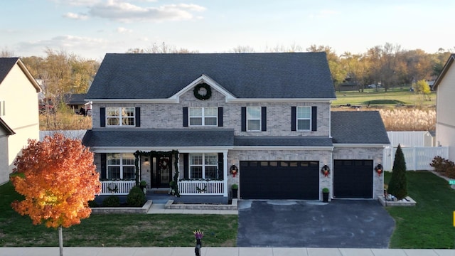 view of front of property with covered porch, a garage, and a front lawn