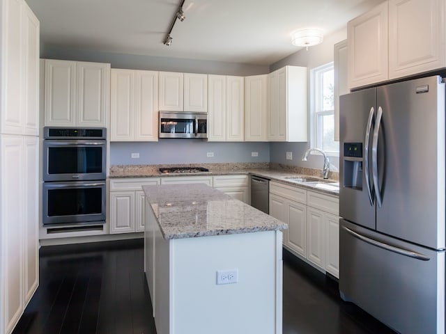 kitchen featuring white cabinetry, sink, stainless steel appliances, dark hardwood / wood-style flooring, and track lighting