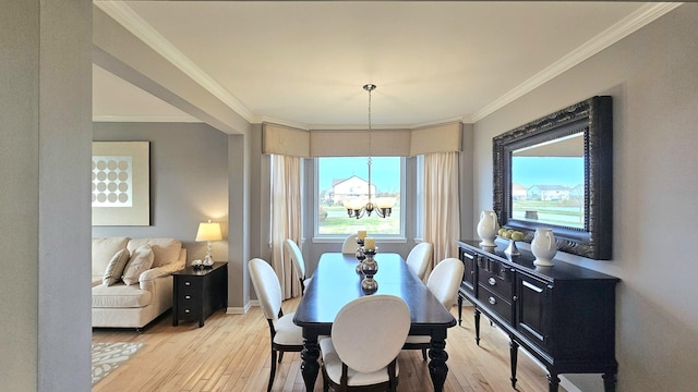 dining area featuring light hardwood / wood-style floors, ornamental molding, and an inviting chandelier