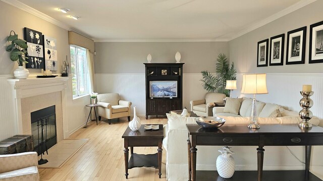 living room with ornamental molding, a tile fireplace, and light hardwood / wood-style flooring