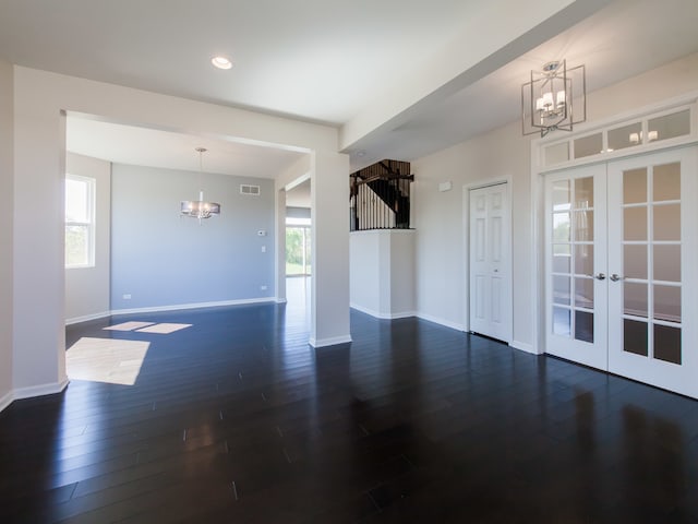 spare room with french doors, dark wood-type flooring, and a notable chandelier