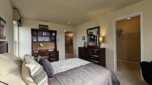 bedroom with a walk in closet, light carpet, and a closet