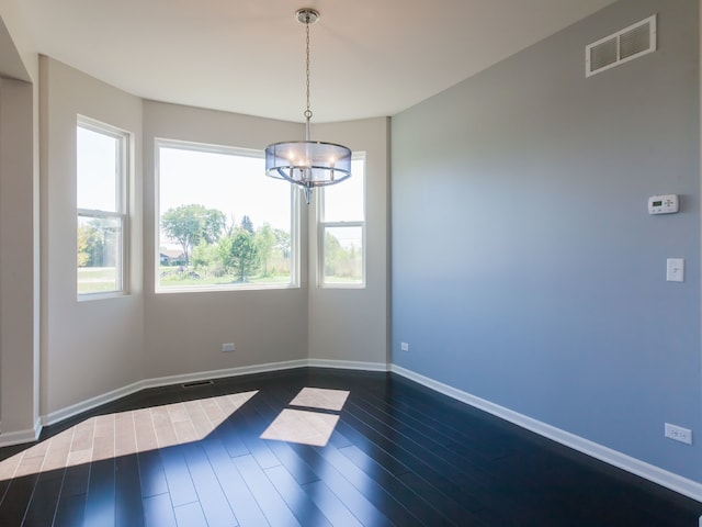 unfurnished dining area featuring dark wood-type flooring and a chandelier