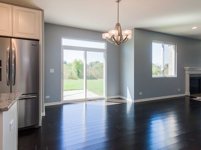 interior space with light stone countertops, pendant lighting, dark hardwood / wood-style flooring, and stainless steel refrigerator