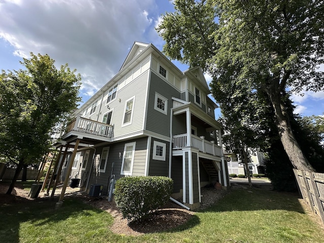 view of side of property featuring a balcony, a yard, and central AC unit