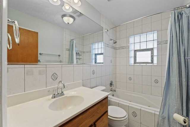 bathroom with toilet, vanity, tile walls, tiled shower / bath, and backsplash