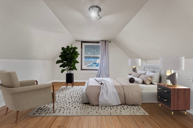 bedroom featuring lofted ceiling, baseboards, and wood finished floors