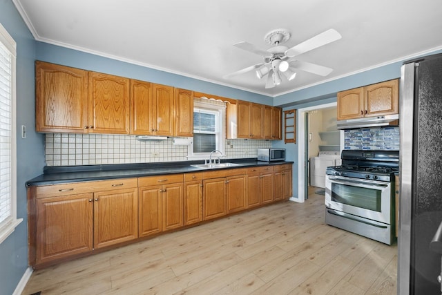 kitchen featuring under cabinet range hood, a sink, light wood-style floors, appliances with stainless steel finishes, and dark countertops