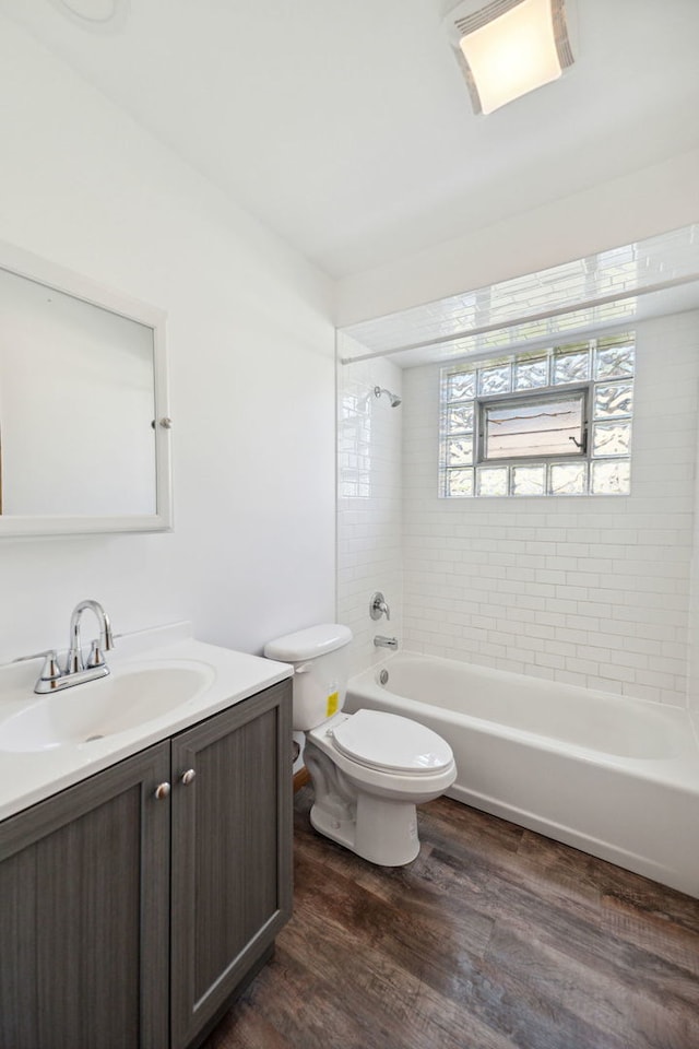 full bathroom featuring vanity, wood-type flooring, tiled shower / bath combo, and toilet