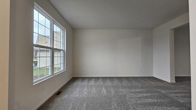 spare room with dark carpet